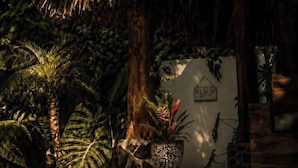 A pool area with a thatched roof, palm trees, and a sign indicating beach access.