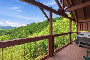 A wooden deck with a hot tub and a view of a forested mountain range. - Cabin w|GORGEOUS Views! Hot Tub! Foliage! Location (Sevierville)