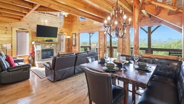 A wooden interior with a dining area, seating, and a fireplace.