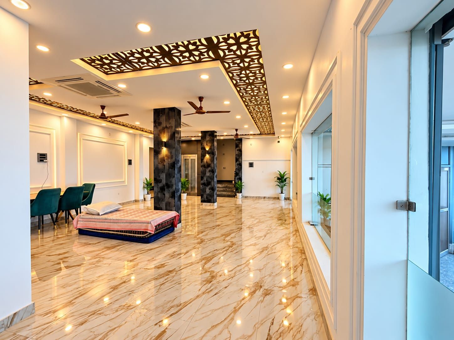 A spacious lobby with a marble floor, a seating area with chairs, a sofa, and decorative pillars.
