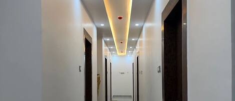 A hallway with a modern design, featuring a glossy floor and recessed lighting.