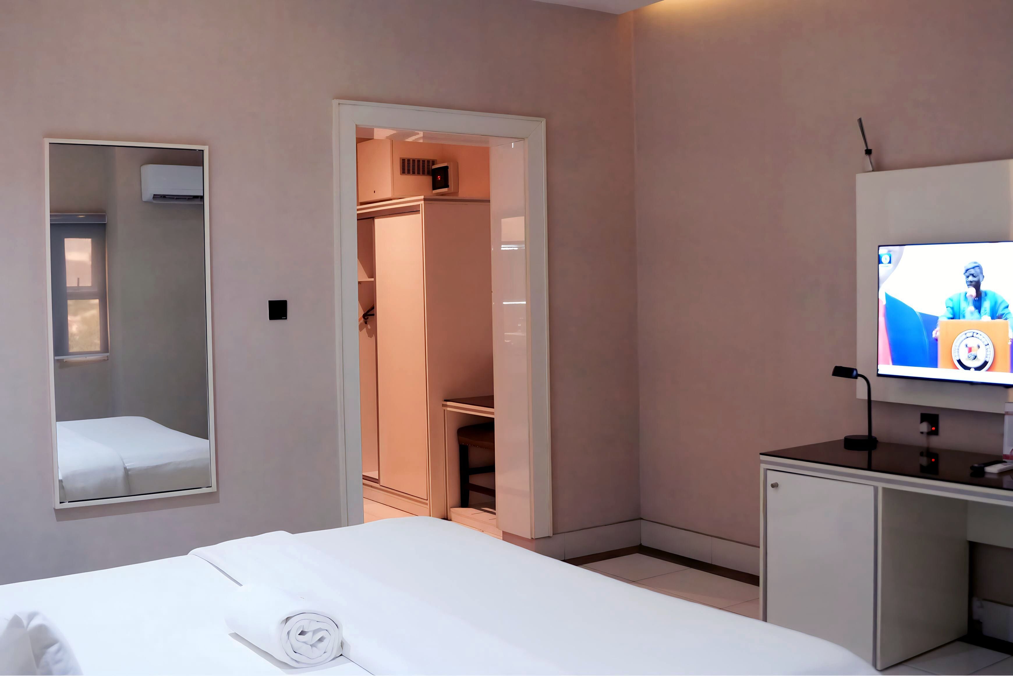 A hotel room with a bed, a desk, a television, and a wardrobe.