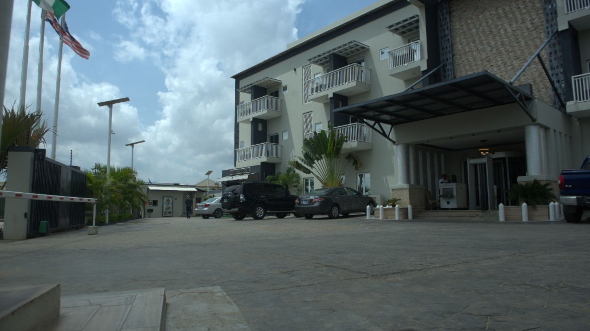 A multi-story hotel with balconies, a parking lot, and a flag.