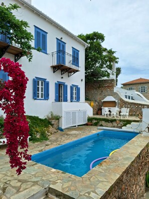 A white building with blue shutters and a stone pool. - Villa Helios - House for 9 people on Hydra (Kiafa). Spectacular view. (Idra)