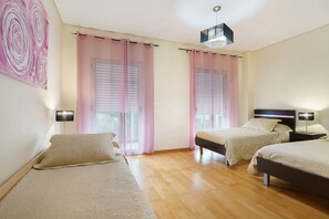 A bedroom with two beds, a ceiling light, and a window with blinds. - Apartment 'T2 Duplex - S Pedro 3' with Sea View, Wi-Fi and Air Conditioning (Ponta Delgada)