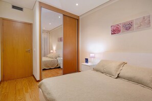 A bedroom with a bed, a nightstand, a lamp, and a mirror. - Apartment 'T3 - Sao Pedro 2' with Sea View, Wi-Fi and Air Conditioning (Ponta Delgada)