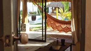 Habitación con vista a una piscina, una hamaca y una mesa con una computadora portátil y una taza.
