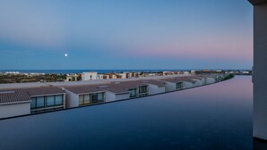 Ett modernt hotell med en pool på taket och utsikt över havet.