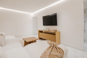 Una sala de estar moderna con un televisor de pantalla plana montado en la pared, una consola de madera y un sofá color beige.