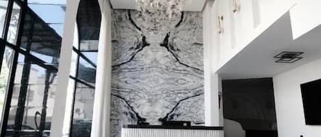 A modern lobby with a marble wall, a black and white patterned floor, and a ceiling with a floral design.