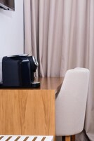 Una mesa de madera con una cafetera negra y una silla blanca.