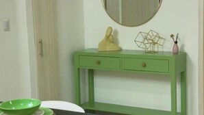 A green console table with a mirror above it, a small statue, and a geometric vase. - Serena Village E5 AP 203 (Punta Cana)