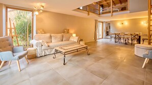 Un salón amplio con sofá, sillones, una mesa de centro y un comedor con mesas y sillas.