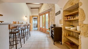 Una cocina con paredes de piedra, taburetes de madera y piso de baldosas.