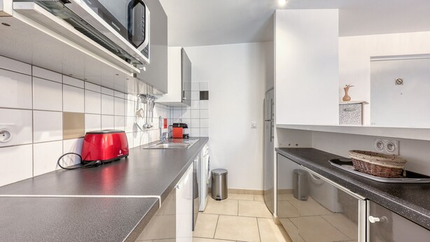 Eine moderne Küche mit weißen Schränken, einer Edelstahl-Spüle, einem roten Toaster und einer Mikrowelle.