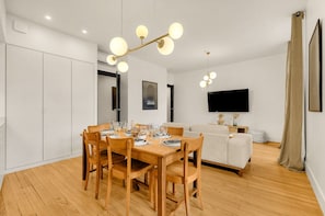Un salon moderne comprenant un coin repas, un canapé, un téléviseur et un lustre.