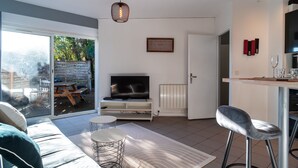 Una sala de estar moderna con televisor, sofá y comedor.