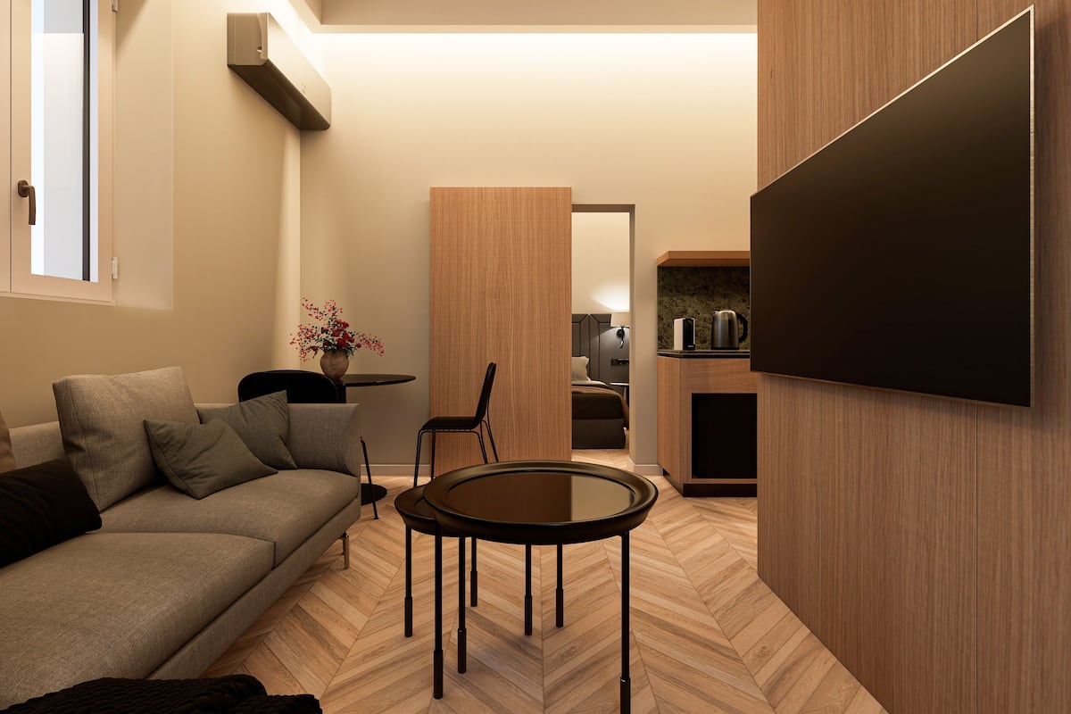 A modern living room with a sofa, a coffee table, and a TV mounted on the wall.