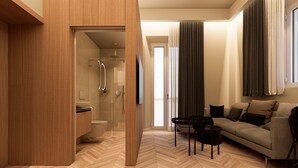Ein modernes Hotelzimmer mit einem Holzschrank, einer Duschkabine aus Glas, einem Sofa und einem Couchtisch.