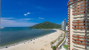Un paysage urbain côtier avec une plage, une montagne et des immeubles de grande hauteur.