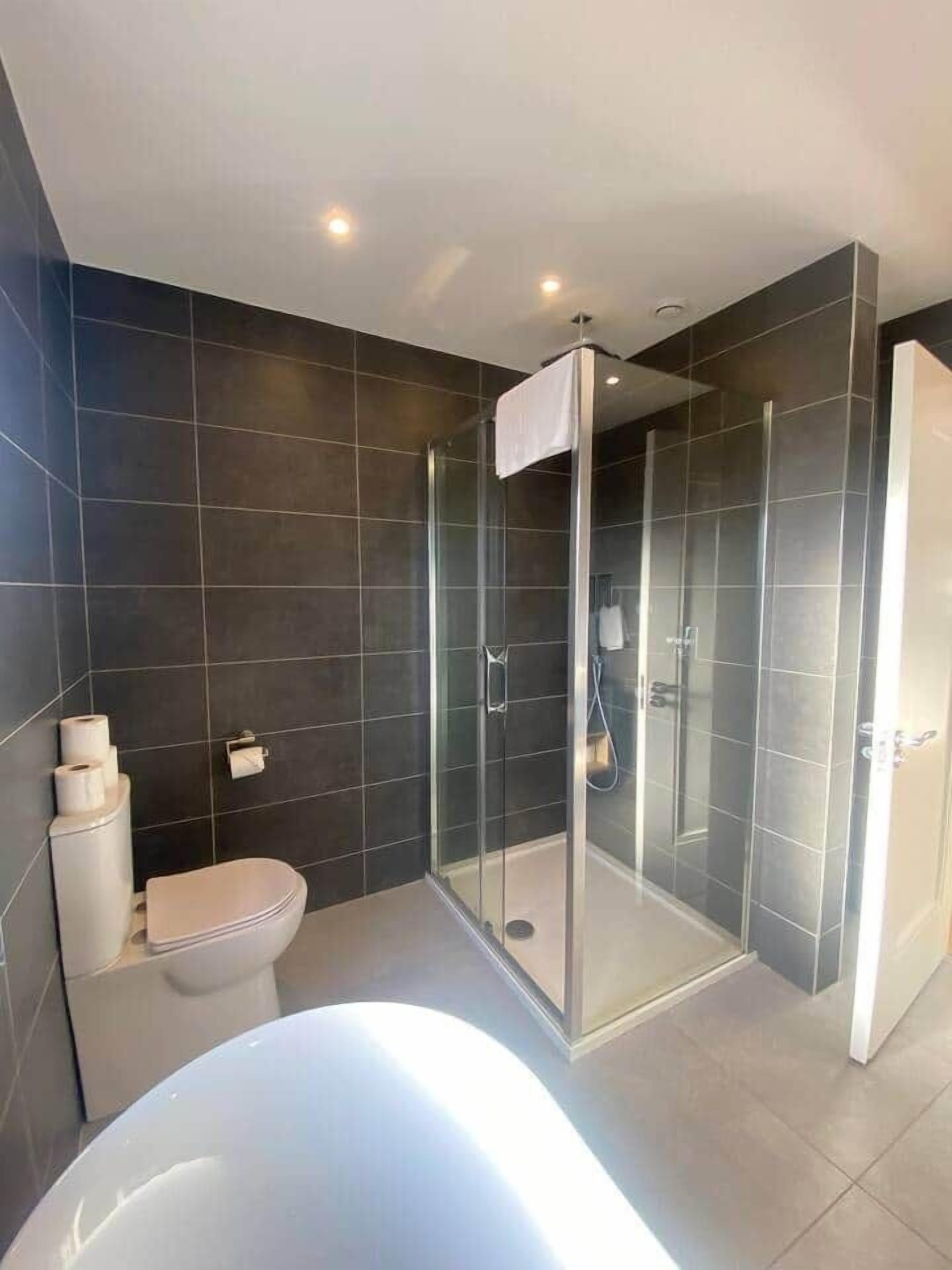 A modern bathroom with a glass-enclosed shower, a white toilet, and a bathtub.