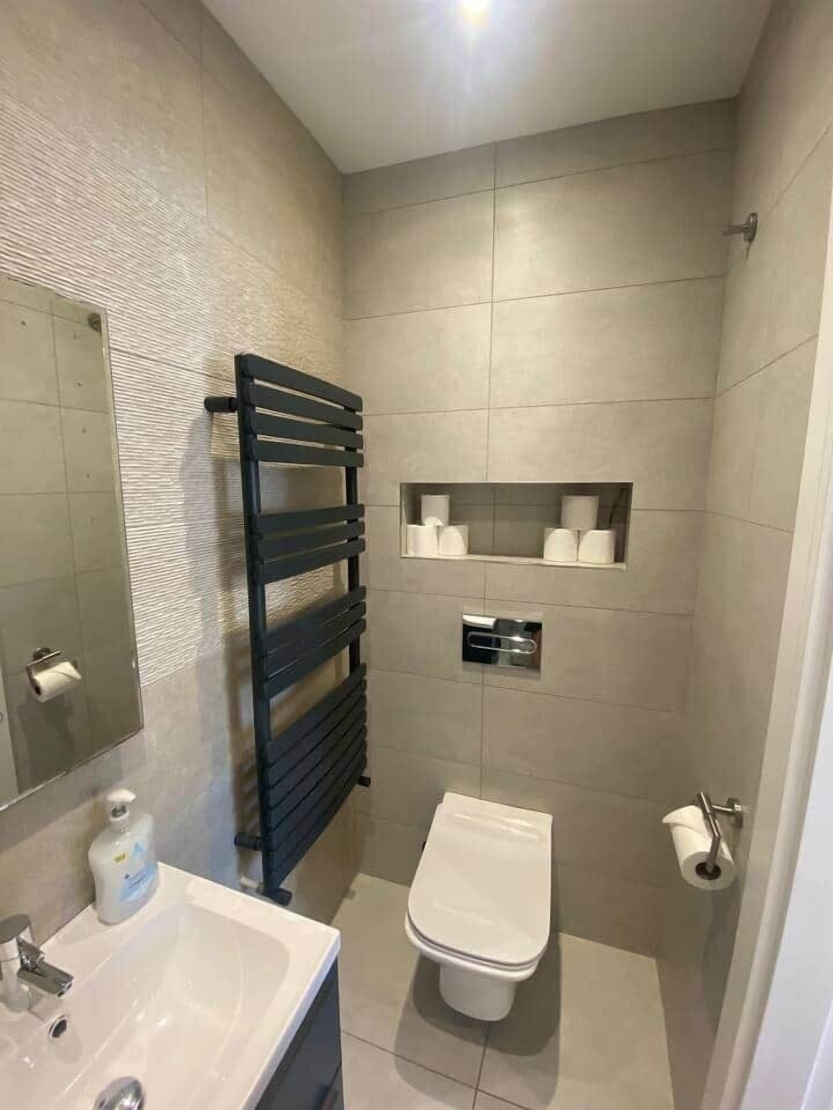 A compact bathroom with a white sink, a toilet, and a towel rack.