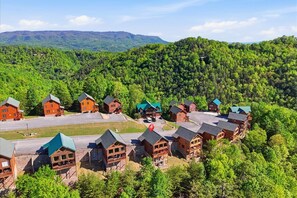 Een lodge met meerdere hutten, omringd door beboste heuvels.