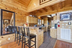 Ein Holzblockhaus-Interieur mit Essbereich, Küche und einem großen Fenster.