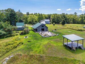 A rural property with a large barn, outdoor seating area, and a well-maintained lawn.