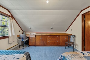 A bedroom with a sloped ceiling, a desk, a chair, a wardrobe, and two beds. - 5-bedroom Lodge on 10 acres great for family reunions, retreats & weddings (Otisfield)