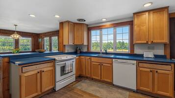 A modern kitchen with wooden cabinets, a central island, and a view of the outdoors.