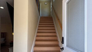 A staircase leading to a second floor with a door on the right and a wall-mounted clock on the left. - New Spacious 3-bedroom house in Beautiful Alhambra (Alhambra)