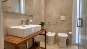 A modern bathroom with a large mirror, a wooden vanity, a bidet, and a toilet. - Acquazzurra Rooms (Castellammare del Golfo)