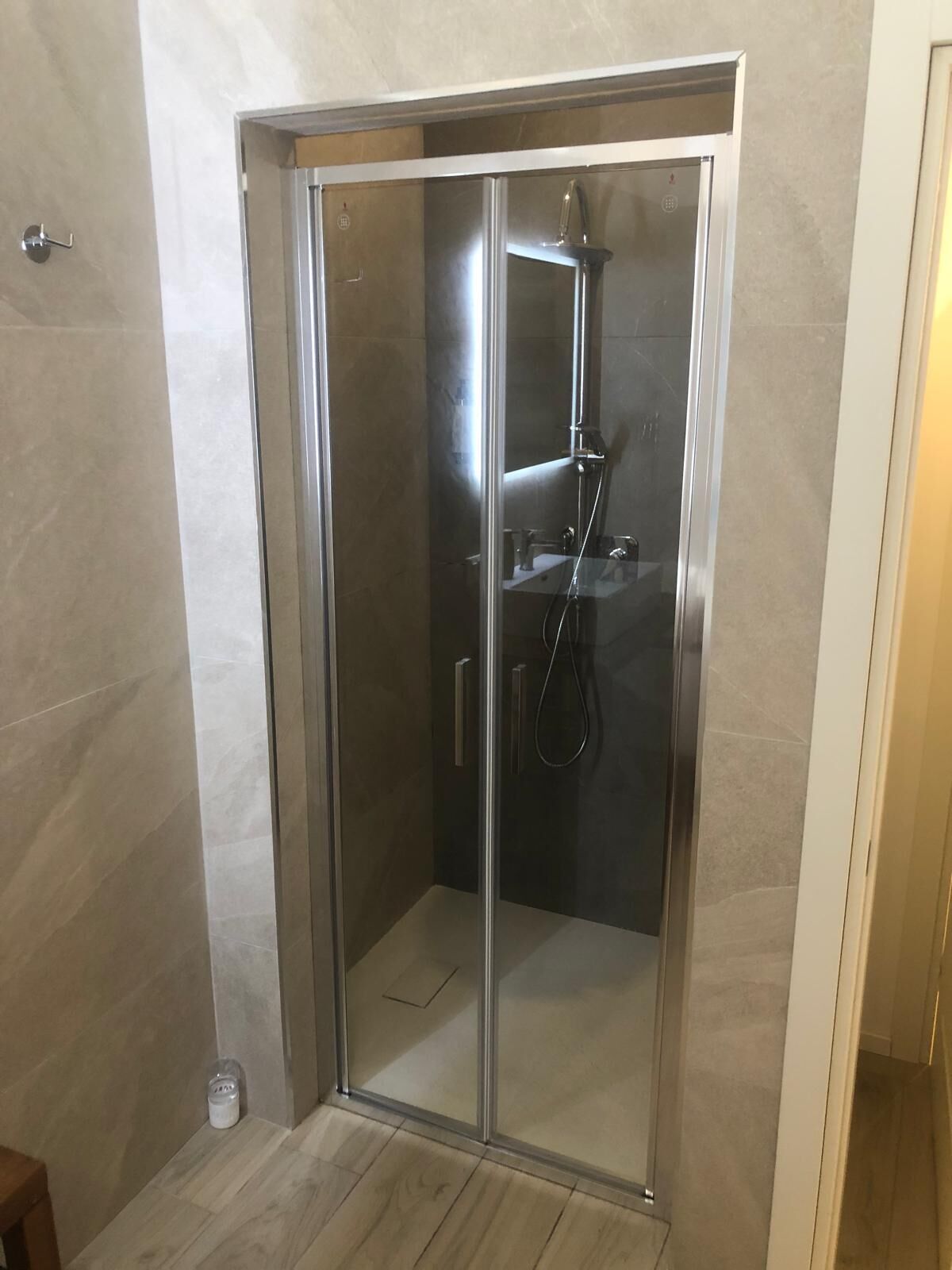A glass-enclosed shower stall with a handheld showerhead and a wall-mounted faucet.