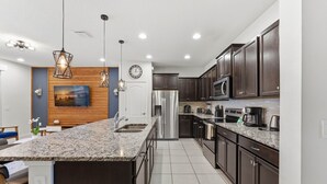 Eine moderne Küche mit Granit Arbeitsplatten, Edelstahlgeräten und dunklen Holzschränken.