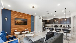 Ein modernes Wohnzimmer mit grauem Sofa, blauem Sessel und einer Wand aus Holz mit einem Gemälde.