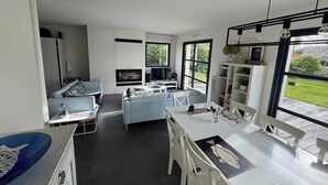 A modern kitchen with a built-in oven, a dining table with chairs, and a large window providing a view of the garden. - Comfortable house for family or friends, walking distance to beach and sea Garden 700 m2 (Saint-Gildas-de-Rhuys)
