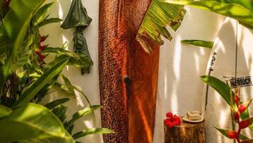 A wooden sculpture with a hole in the center, surrounded by lush green foliage and a small tree stump.