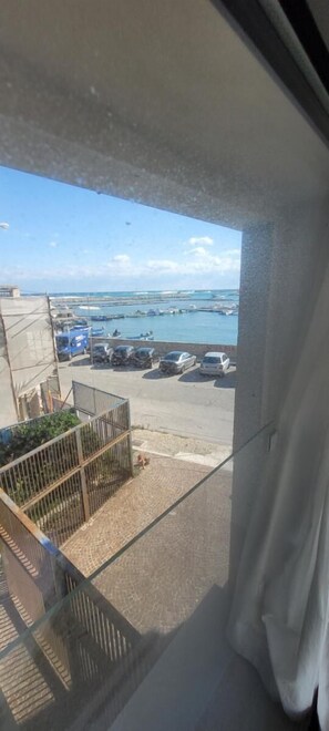 Uitzicht vanaf een balkon over een jachthaven met geparkeerde auto's en boten.