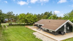 Ein modernes Haus mit einer großen Terrasse, einer separaten Garage und einem gepflegten Rasen.