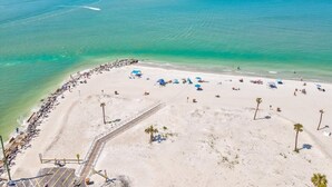 Una playa con agua turquesa cristalina, una orilla arenosa y varios sombrillas y personas.