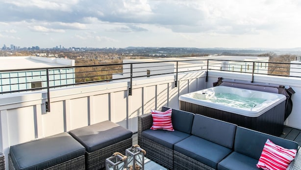 Une terrasse sur le toit avec un jacuzzi, un espace salon et une vue sur la ville.