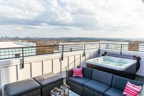 Une terrasse sur le toit avec un jacuzzi, un espace salon et une vue sur la ville.