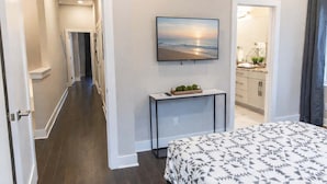 Une chambre d’hôtel avec un lit, un téléviseur fixé au mur, une petite console sur laquelle est posé un panier de fruits, et une vue sur l’océan par la fenêtre.