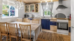 Eine moderne Küche mit Holzausbau, einem eingebauten Backofen und einem Essbereich mit Holztischen und einer Tischplatte.