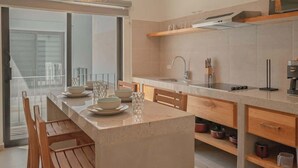 A modern kitchen with a central island, wooden chairs, a large window, and a built-in oven. - Palma 302 La Paz Downtown 2BR Suite Parking & Pool (La Paz)