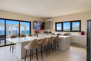 A modern kitchen with a large island, bar stools, and a view of the ocean.
