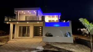 Et moderne hus med to etager, en balkon, store vinduer og en lys indgang.