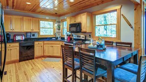 Une cuisine rustique, située dans une cabane en bois, avec un îlot central, des armoires en bois et un four à micro-ondes.