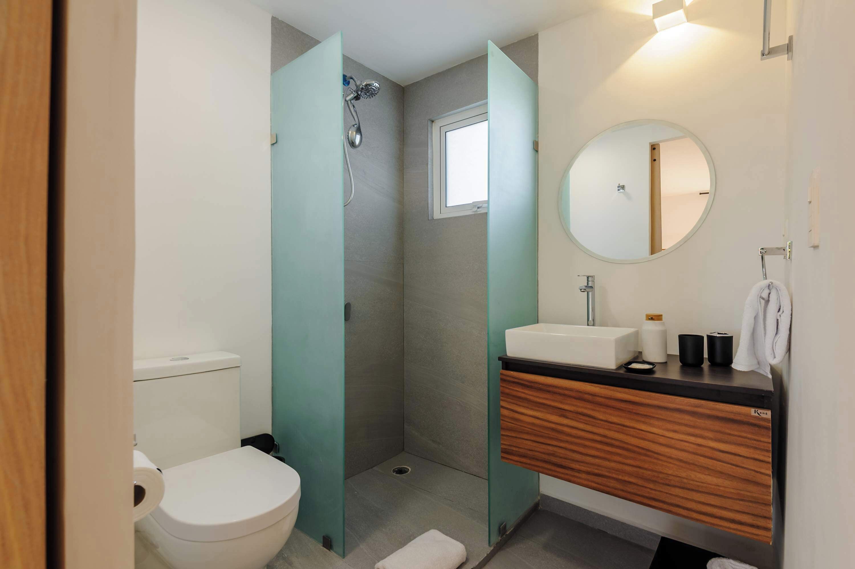 Une salle de bain moderne équipée de toilettes, d’une douche et d’un meuble-lavabo avec un miroir.